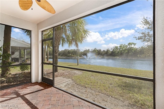 unfurnished sunroom featuring a water view and ceiling fan