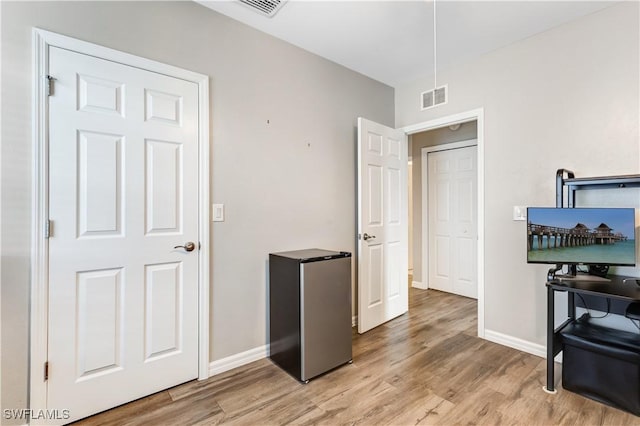 interior space featuring light wood-type flooring, baseboards, and visible vents