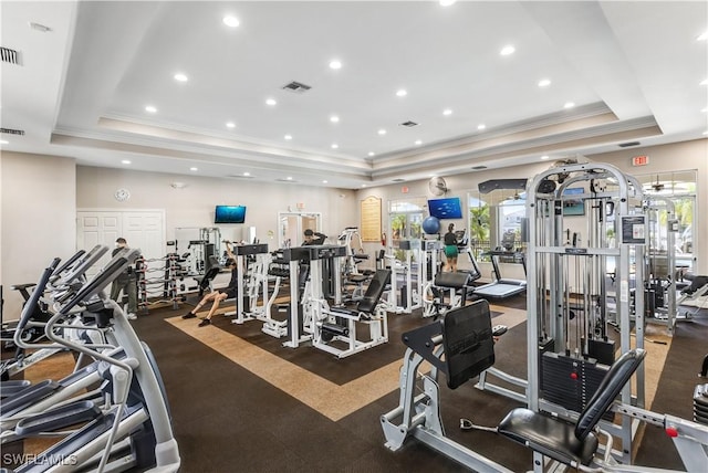 workout area with a tray ceiling and ornamental molding