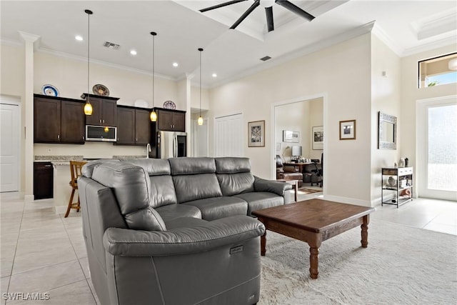 living room with ceiling fan, light tile patterned flooring, a towering ceiling, and ornamental molding