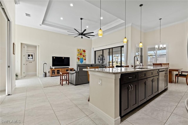 kitchen with a kitchen island with sink, ceiling fan with notable chandelier, sink, light stone countertops, and decorative light fixtures