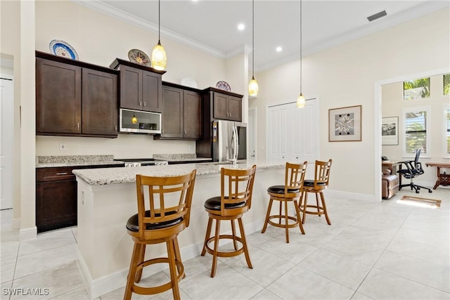 kitchen with pendant lighting, stainless steel appliances, a breakfast bar area, and an island with sink