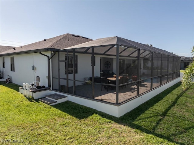 back of house with a lanai, a patio area, and a yard