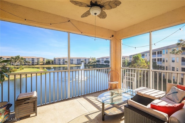 sunroom with ceiling fan and a water view