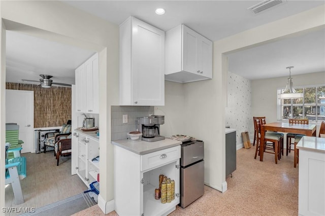 kitchen featuring light countertops, wallpapered walls, visible vents, and white cabinets