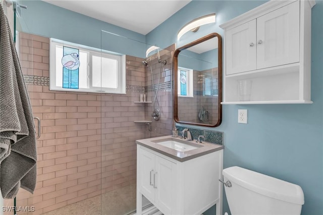 bathroom featuring toilet, a tile shower, and vanity