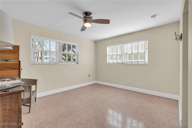 unfurnished office featuring baseboards, light speckled floor, and a ceiling fan