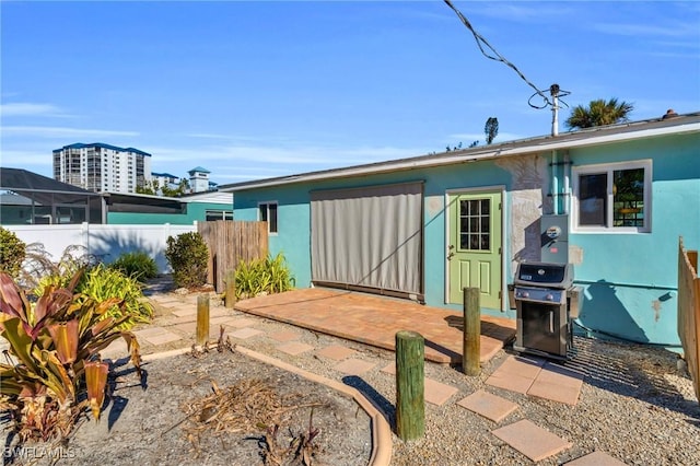 rear view of house featuring a patio area, fence, and stucco siding