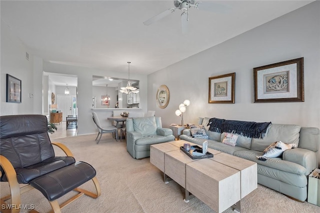 living room with ceiling fan with notable chandelier and light colored carpet