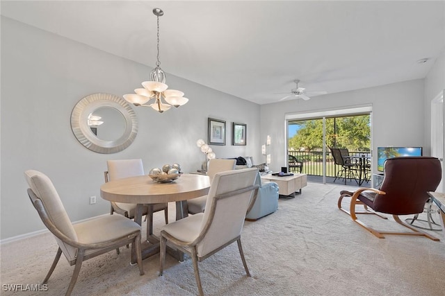 carpeted dining area with ceiling fan with notable chandelier