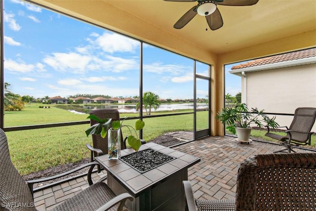 sunroom / solarium featuring a water view and ceiling fan