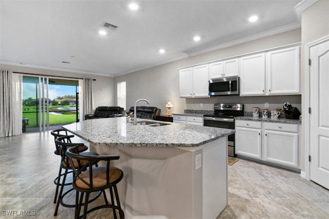 kitchen with a center island with sink, sink, light stone countertops, white cabinetry, and stainless steel appliances