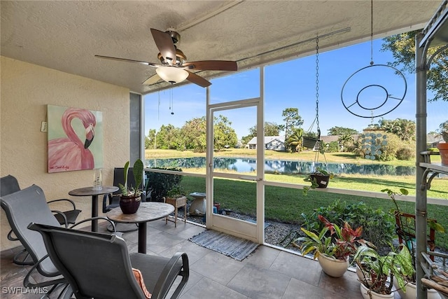 sunroom / solarium featuring ceiling fan and a water view