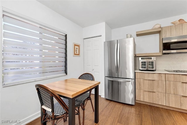 kitchen featuring light brown cabinets, stainless steel appliances, and light hardwood / wood-style floors