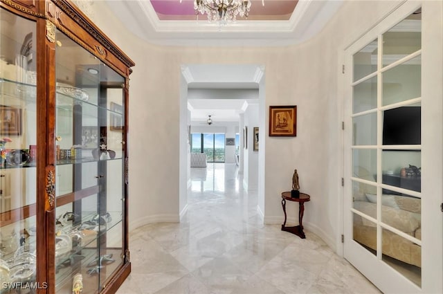 corridor with crown molding, a notable chandelier, and a tray ceiling