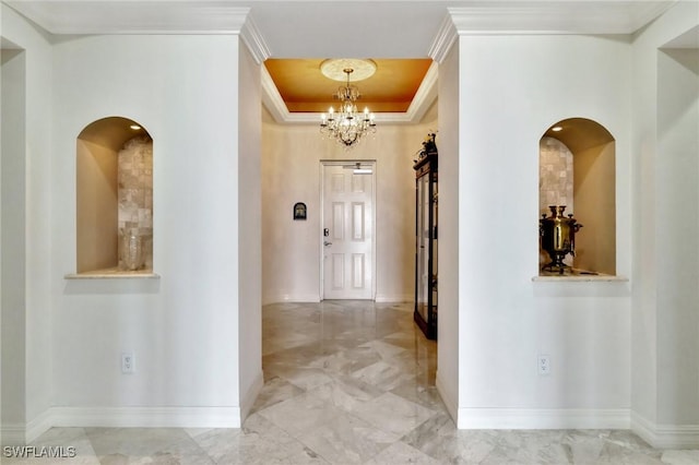 hallway with a tray ceiling, crown molding, and a chandelier