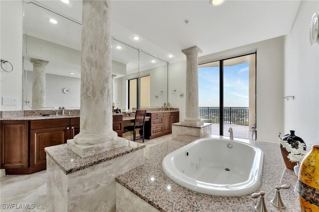 bathroom with decorative columns, vanity, and a relaxing tiled tub