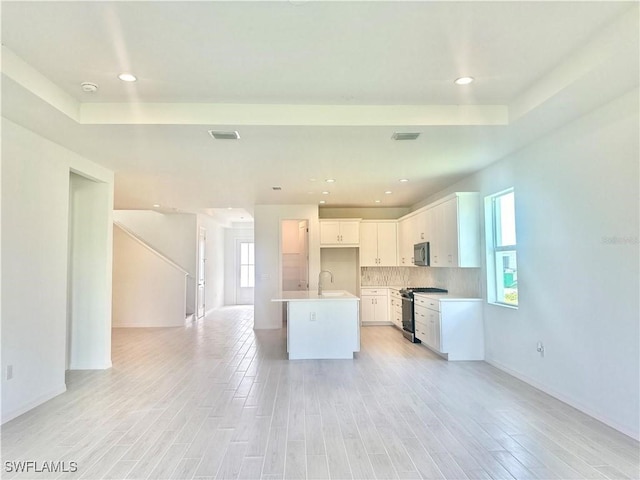 kitchen featuring sink, appliances with stainless steel finishes, light hardwood / wood-style floors, an island with sink, and white cabinets