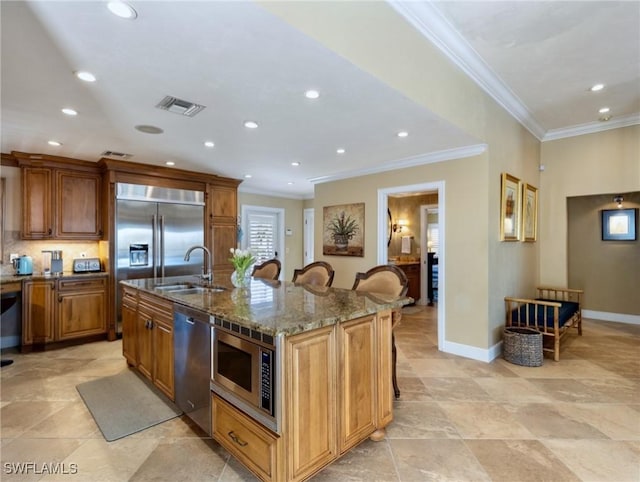 kitchen featuring built in appliances, sink, a kitchen bar, and a kitchen island with sink