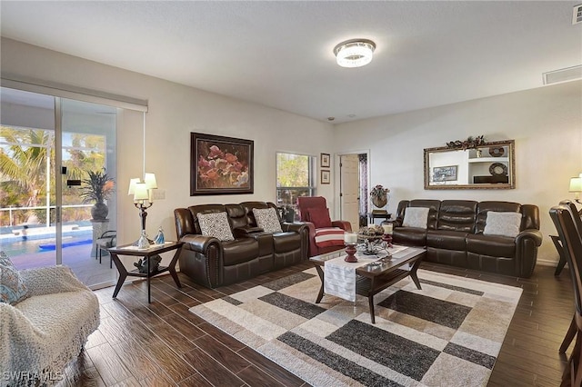 living room with a healthy amount of sunlight and dark wood-type flooring