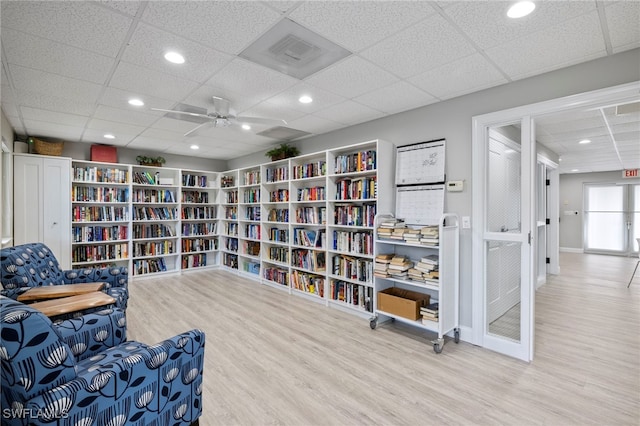 sitting room featuring ceiling fan, a drop ceiling, and wood-type flooring