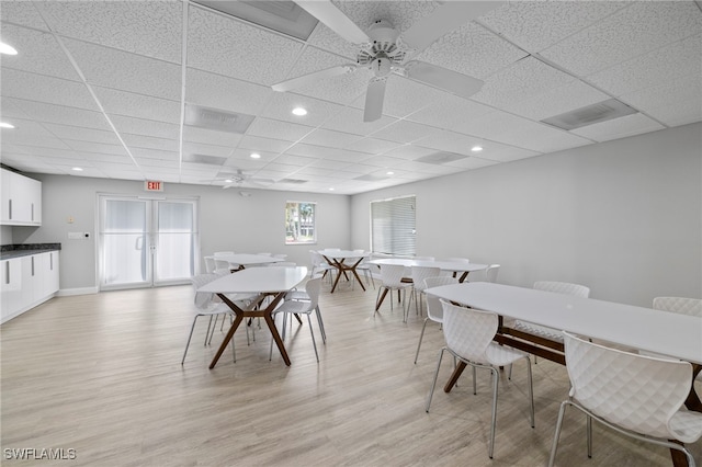 dining area with a paneled ceiling, ceiling fan, and light hardwood / wood-style flooring