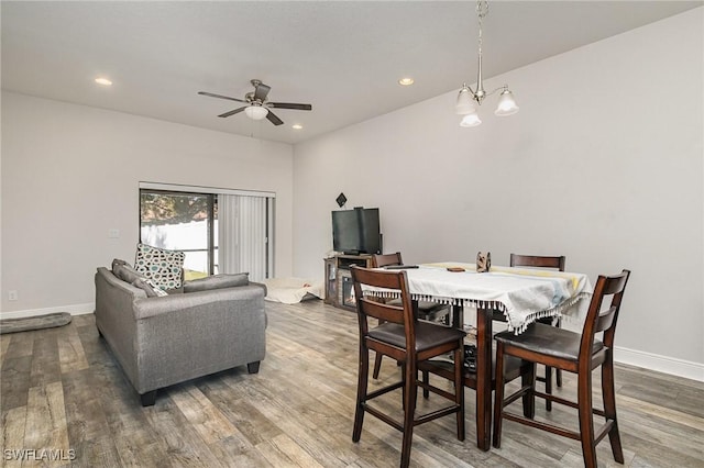 dining area featuring ceiling fan with notable chandelier and dark wood-type flooring