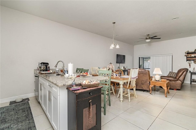 kitchen featuring white cabinetry, sink, hanging light fixtures, light stone counters, and ceiling fan with notable chandelier