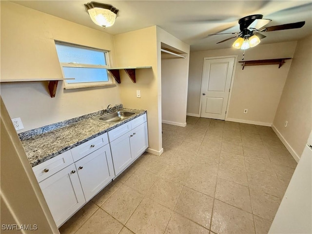 kitchen with ceiling fan, white cabinets, sink, and dark stone countertops