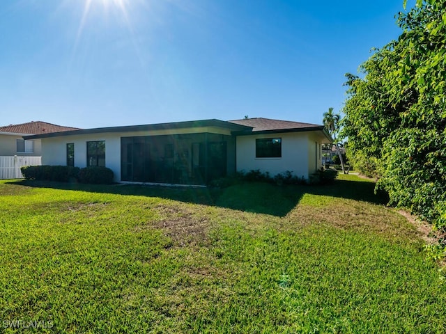 view of side of property featuring stucco siding, fence, and a yard