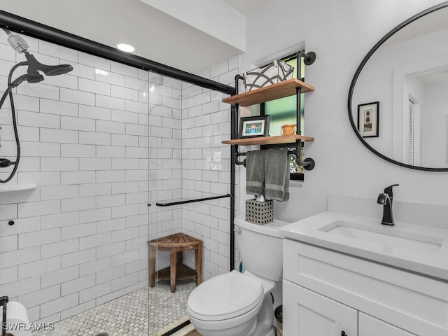 bathroom with a tile shower, vanity, and toilet