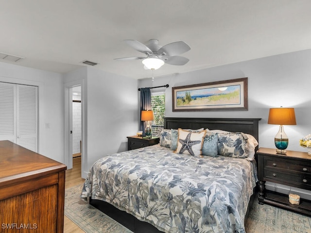 bedroom with a closet, wood finished floors, visible vents, and a ceiling fan