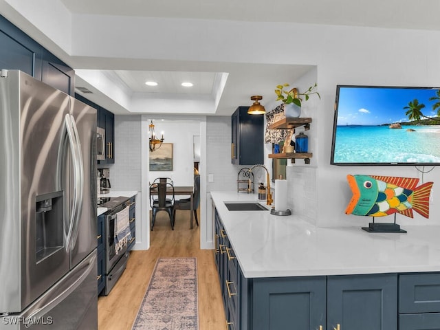 kitchen with sink, a raised ceiling, light hardwood / wood-style flooring, a chandelier, and appliances with stainless steel finishes