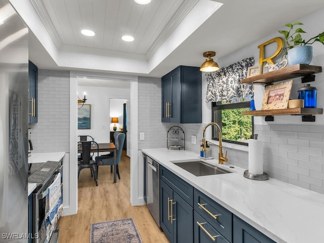 kitchen with light wood-style flooring, ornamental molding, blue cabinets, a tray ceiling, and a sink