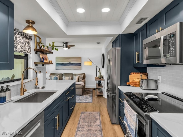 kitchen with visible vents, appliances with stainless steel finishes, ornamental molding, a sink, and blue cabinets