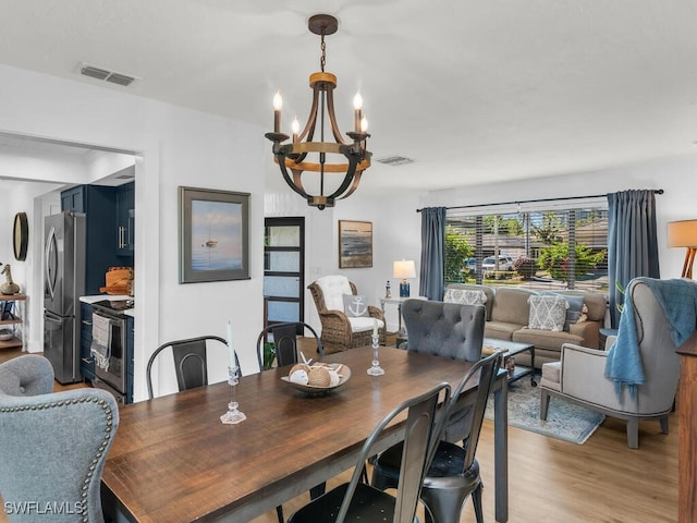 dining area with light hardwood / wood-style floors and an inviting chandelier