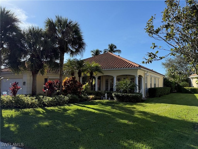 mediterranean / spanish house with a garage, stucco siding, a front lawn, and a tiled roof