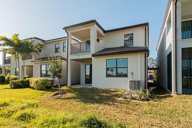 back of property featuring a lawn, a balcony, and central air condition unit