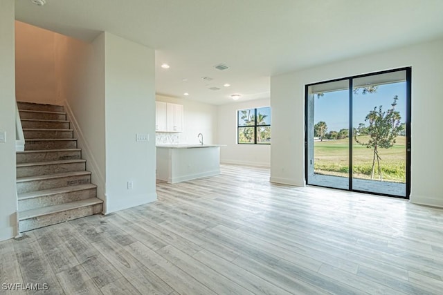 unfurnished living room with sink and light wood-type flooring