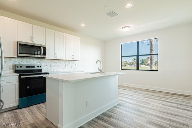 kitchen with sink, stainless steel appliances, light hardwood / wood-style floors, a center island with sink, and white cabinets