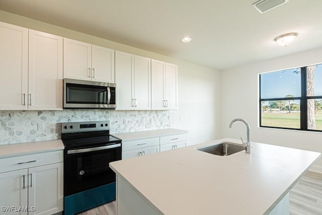 kitchen with white cabinetry, sink, a center island with sink, and appliances with stainless steel finishes