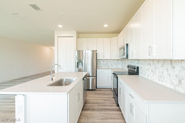 kitchen featuring a kitchen island with sink, sink, white cabinets, and appliances with stainless steel finishes