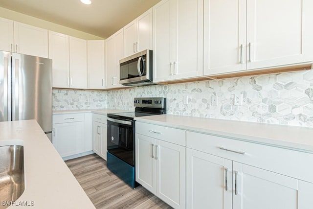 kitchen with white cabinets, backsplash, stainless steel appliances, and light hardwood / wood-style floors