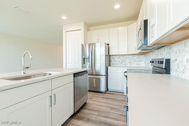 kitchen featuring white cabinets, stainless steel appliances, light hardwood / wood-style flooring, and sink