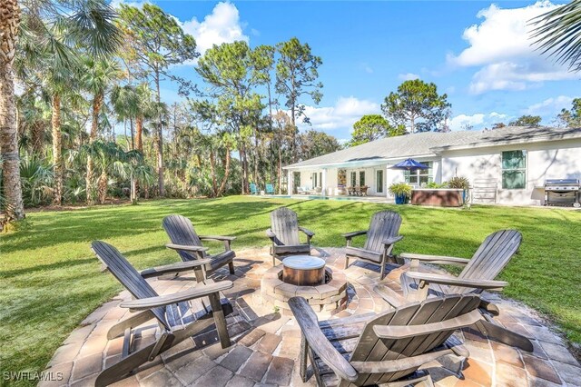 view of patio / terrace with an outdoor fire pit, grilling area, and a hot tub