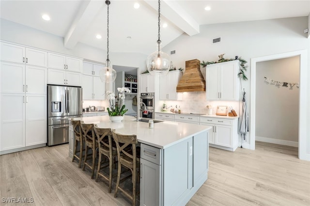 kitchen featuring stainless steel appliances, white cabinetry, premium range hood, and an island with sink