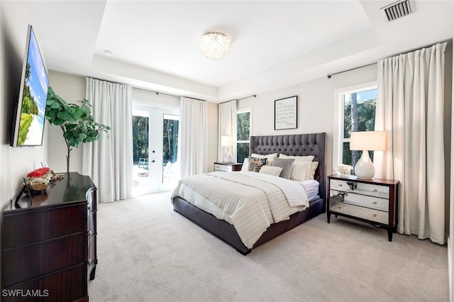 carpeted bedroom featuring a raised ceiling, access to exterior, and french doors