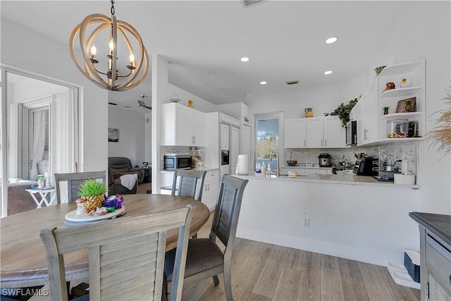 dining area featuring light wood-type flooring, an inviting chandelier, and sink