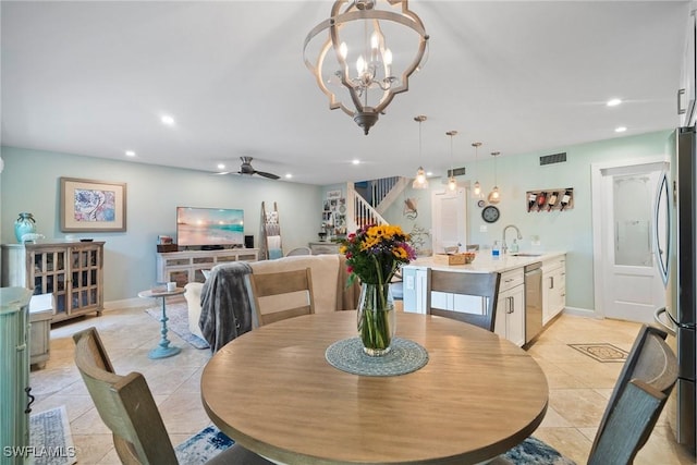 dining room with light tile patterned flooring, ceiling fan with notable chandelier, and sink