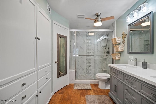 bathroom with vanity, toilet, wood-type flooring, and a shower with door